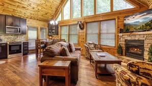 A log cabin interior with a kitchen, dining area, and fireplace. - Smoky Mountain Escape-Hot Tub, Game Room, & Resort Pool , WIFI (Gatlinburg)