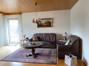 Een woonkamer met een bank, een salontafel, een vloerkleed, een schilderij en een lamp.