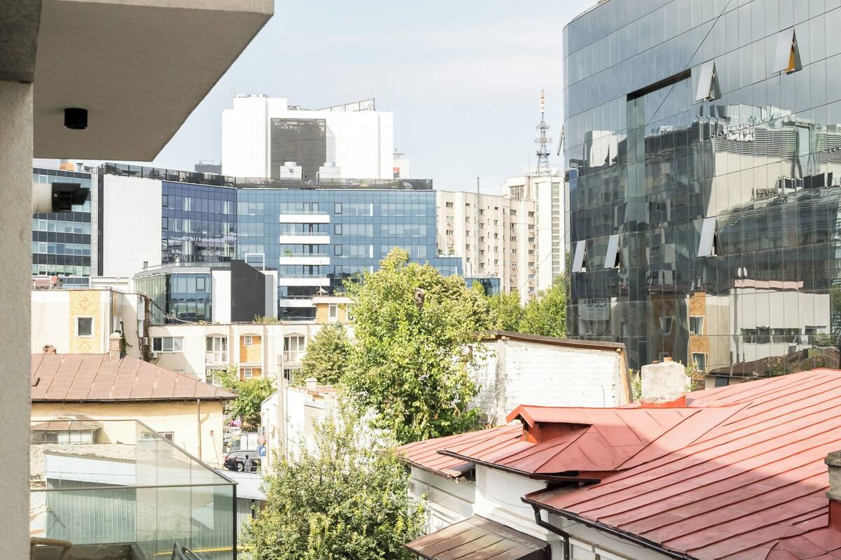 A modern urban landscape with a mix of residential and commercial buildings, including a prominent glass building reflecting its surroundings.
