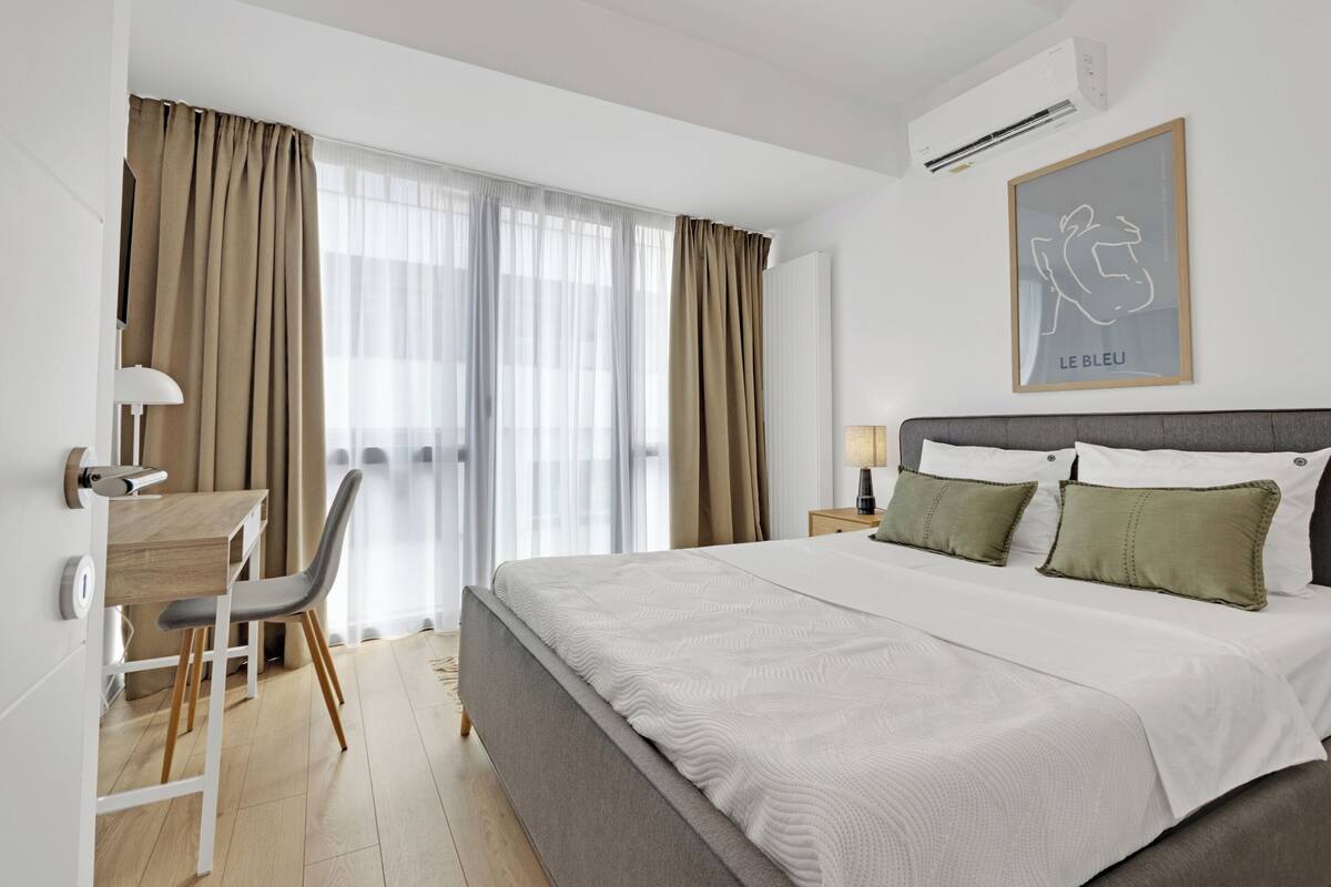 A modern hotel room with a large bed, a desk, and a chair.
