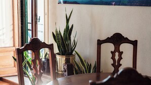 Un coin repas avec une table en bois, des chaises, une plante en pot et un appareil photo ancien.