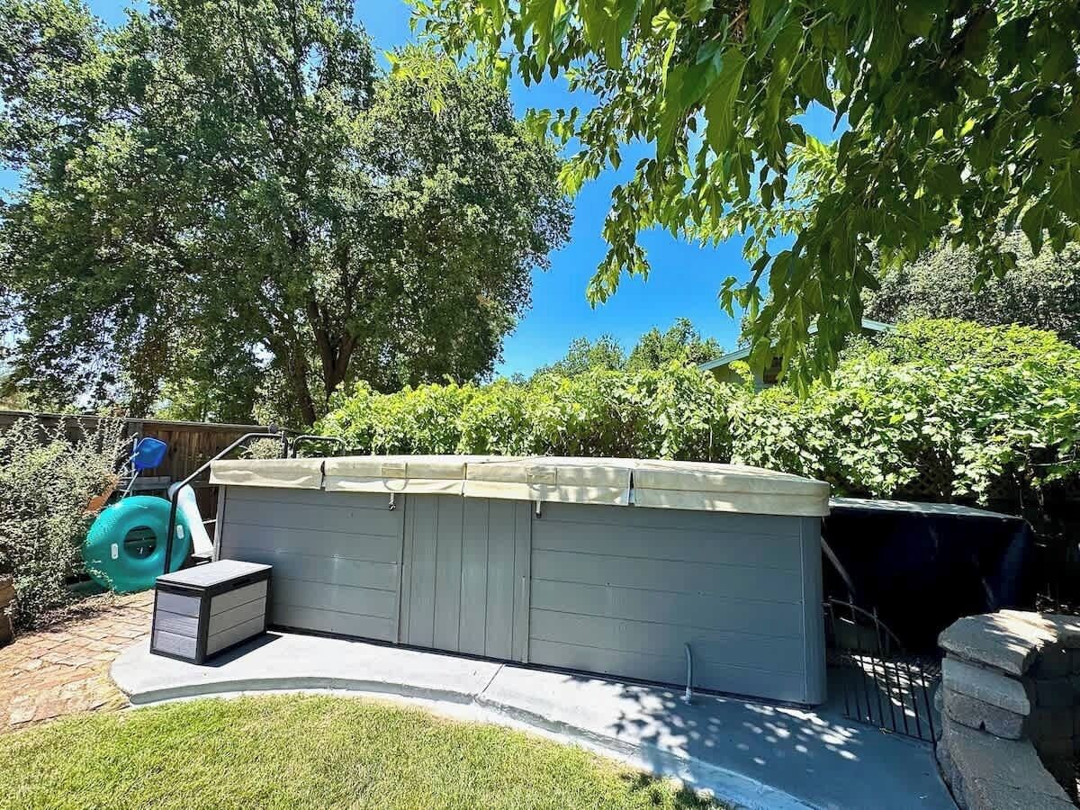 Un espace de stockage extérieur abrité, doté d’un sol en béton et entouré de verdure et d’arbres.