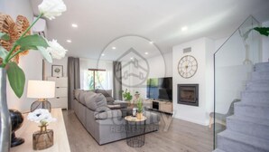 Ein modernes Wohnzimmer mit einem grauen Sofa, einem Fernseher, einem Kamin und einer Treppe.