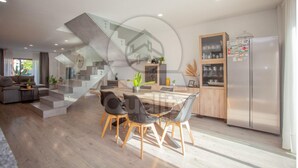 Eine moderne Küche mit einer Glaswendeltreppe, einem Essbereich mit Glastisch und einer eingebauten Kabine mit Glastüren.