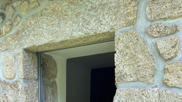 A stone-walled room with a bed and a small table. - Paredes de Coura Villa (Paredes de Coura)