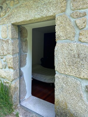 A stone-walled room with a bed and a small table. - Paredes de Coura Villa (Paredes de Coura)