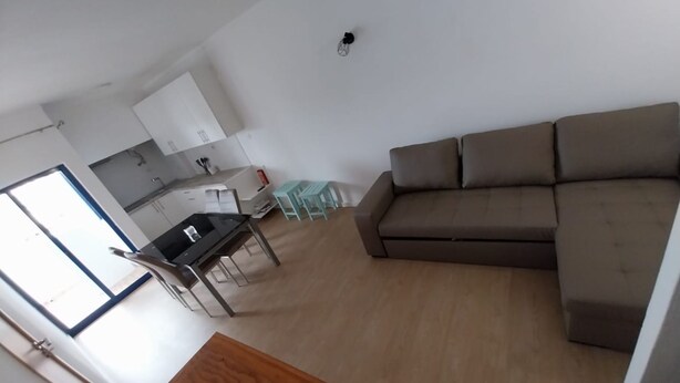 A modern living room with a brown sofa, a wooden coffee table, and a dining area with a small table and chairs. - Clube Praia da Rocha Balcony J 138 (Portimão)