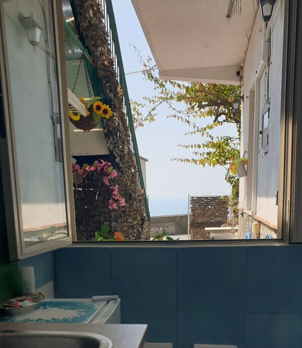 Ein Badezimmer mit Fensterblick auf einen Balkon, der mit Sonnenblumen und einem Baum geschmückt ist.