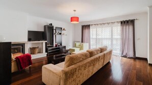 Una sala de estar con sofá, televisión y chimenea.