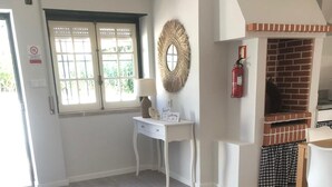 Un salon moderne avec un canapé gris, un bureau blanc et un four en briques.
