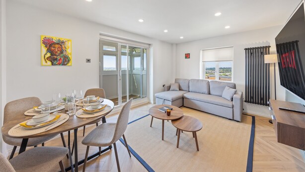 A modern living room with a dining area, a sofa, and a TV.