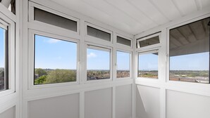 A room with white paneled walls and multiple windows offering a view of a cityscape.
