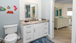 A bathroom with a toilet, sink, and cabinets. There are decorative fish on the wall. - Just Chill Modern Canal Villa w Heated Pool (Cape Coral)