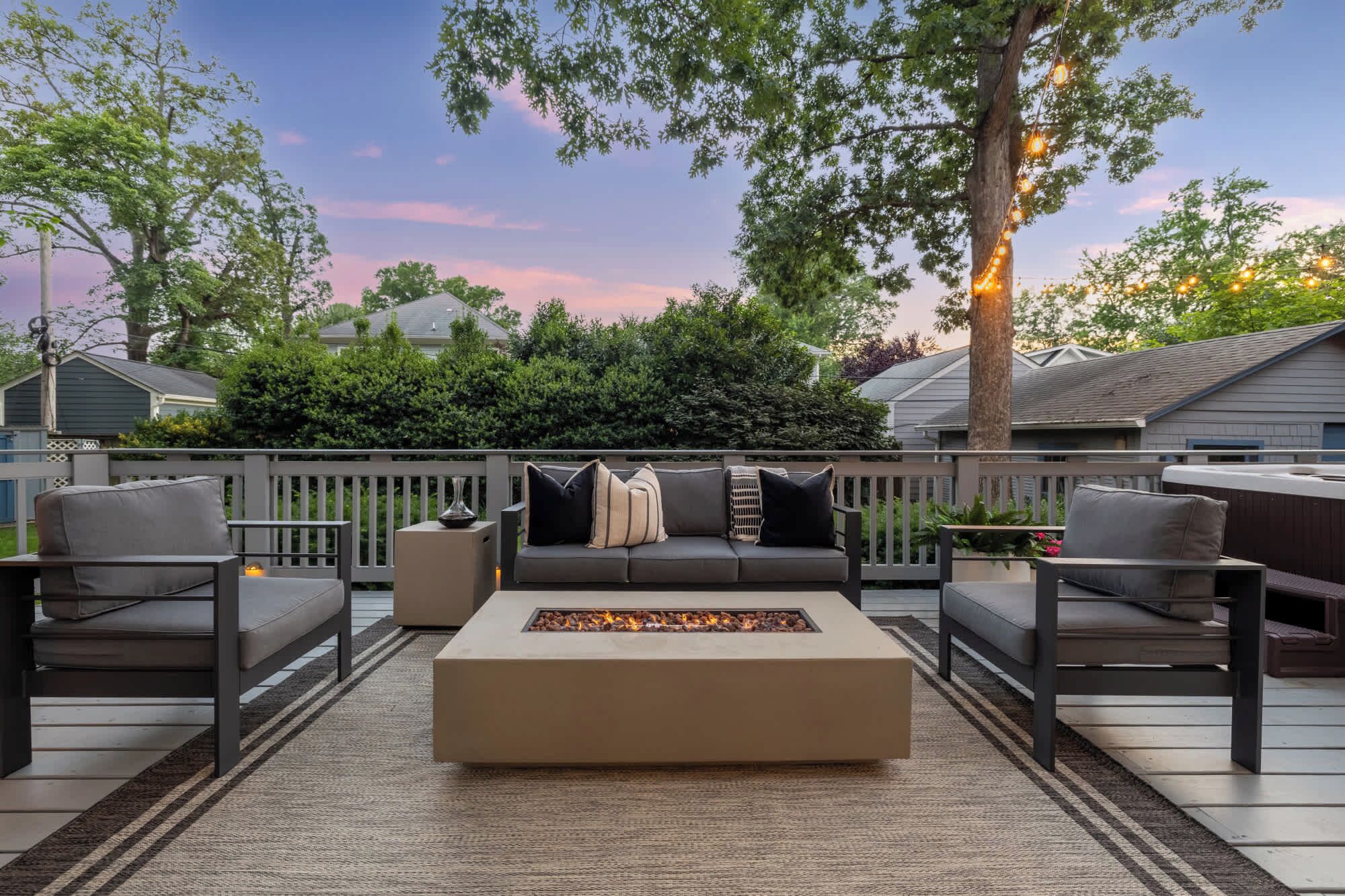 An outdoor deck with a fire pit, seating, and a view of the neighborhood.