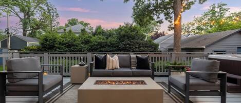 An outdoor deck with a fire pit, seating, and a view of the neighborhood.
