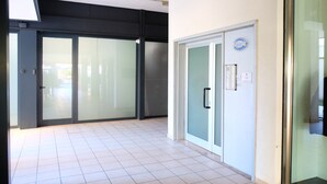 A modern interior with a tiled floor, a glass door with a handle, and a wall-mounted sign. - Apartment 'Ellidor 01' with Private Terrace and Air Conditioning (Lido di Jesolo)