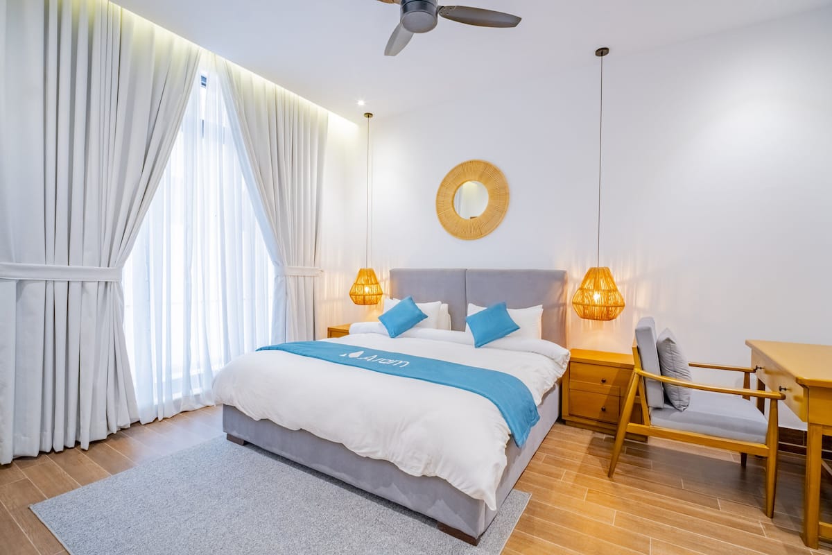 A modern bedroom with a bed, bedside tables, a desk, and a chair.