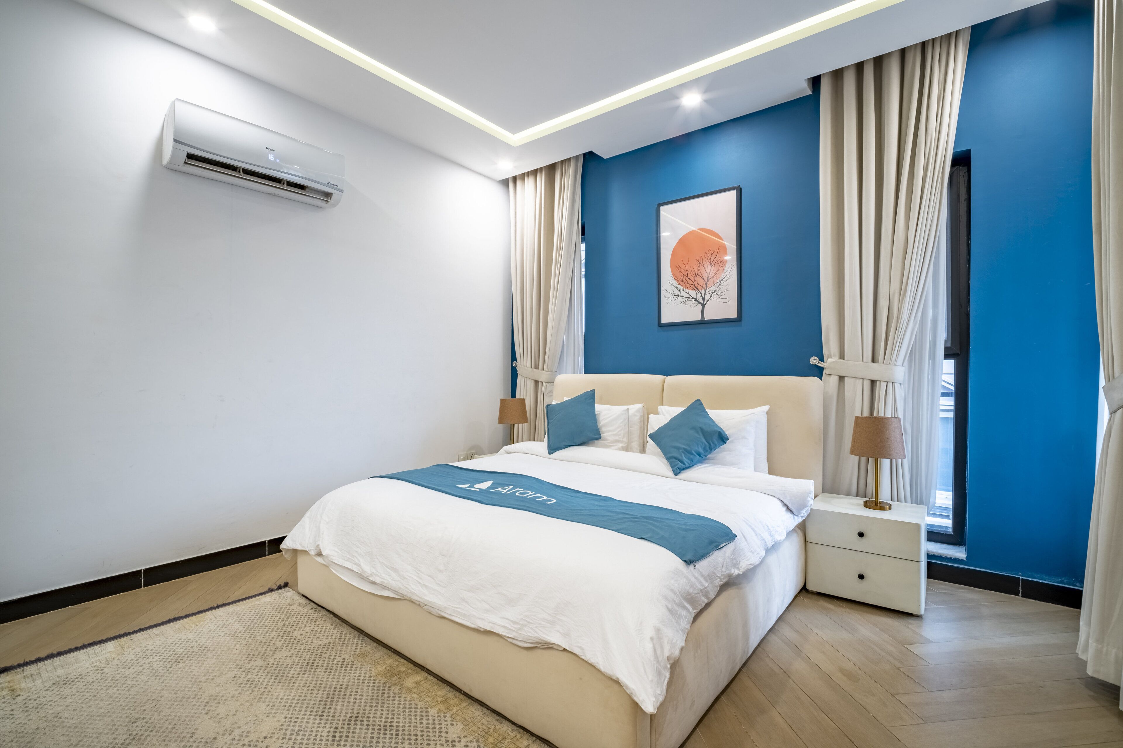 Une chambre d’hôtel moderne dotée d’un grand lit, de tables de chevet, d’un appareil de climatisation et d’une fenêtre avec des rideaux.