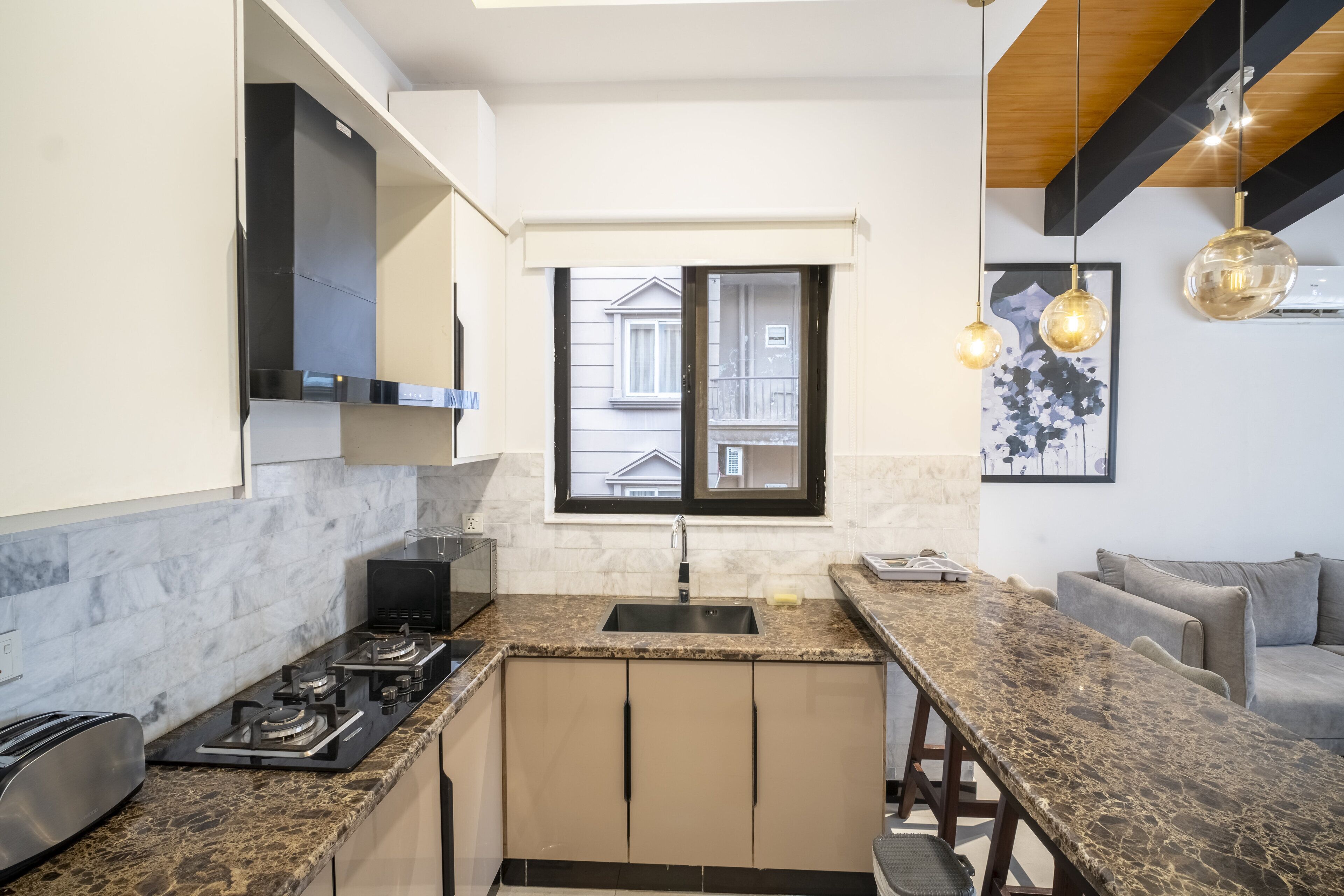 Een moderne keuken met een centraal eiland, een inbouwoven en een raam met uitzicht op de straat.