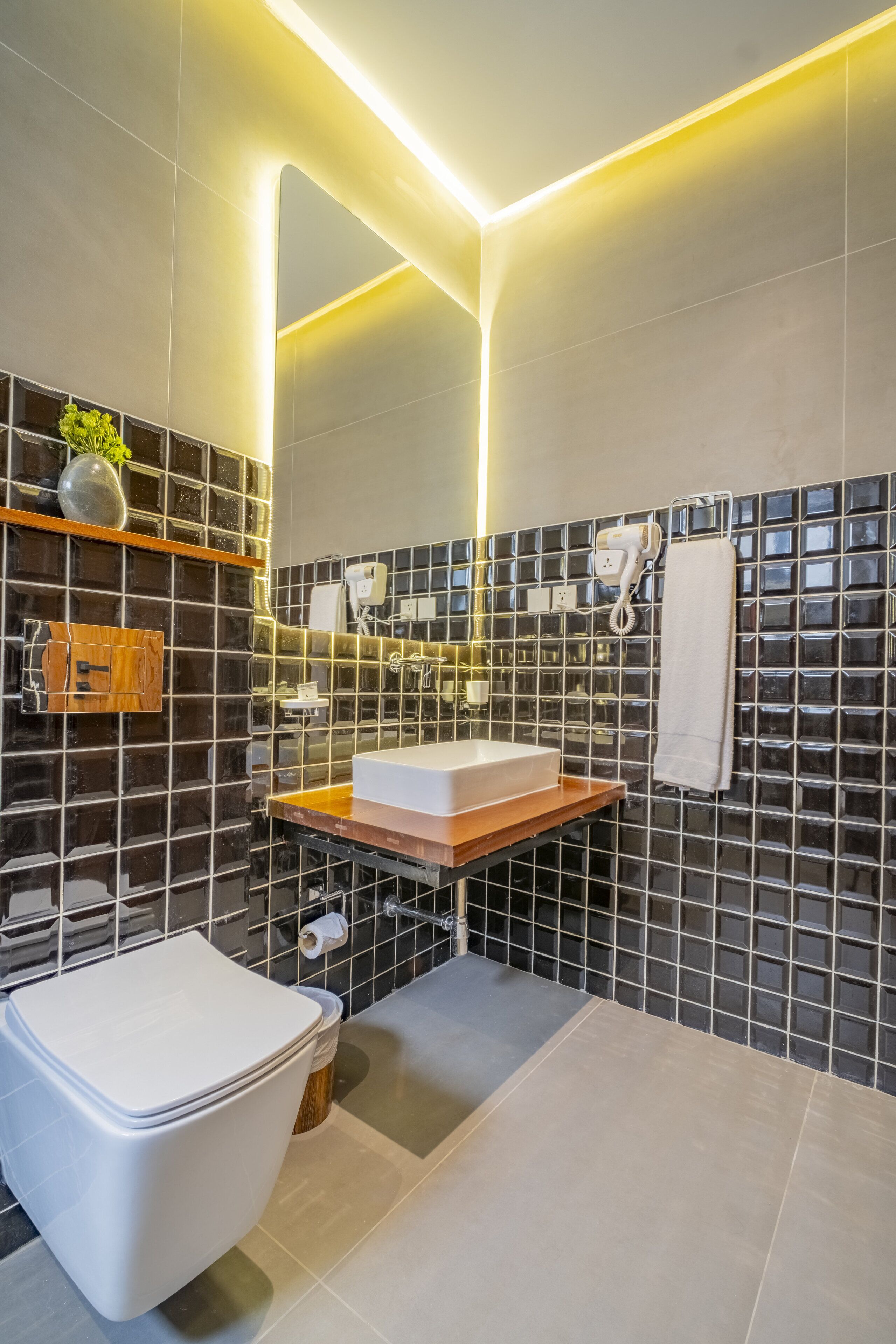 A modern bathroom with a white toilet, a wooden vanity, a mirror, and a towel rack.