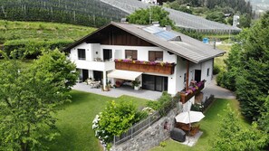 A two-story house with a balcony, a covered patio, and a garden.
