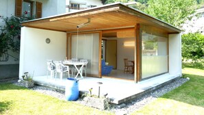A modern house with a covered patio, a dining area, and a view of a mountainous landscape.