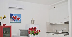 A kitchen with white cabinets, a built-in stove, a sink, and a small television.