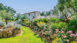 A house with a garden featuring a variety of plants and flowers. - Beautiful private villa for 6 guests with A/C, private pool, WIFI, TV and patio (Trequanda)