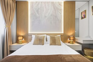 Una camera d'albergo moderna con un letto grande, due comodini con lampade, uno specchio ampio e una parete decorata con un motivo a foglia.