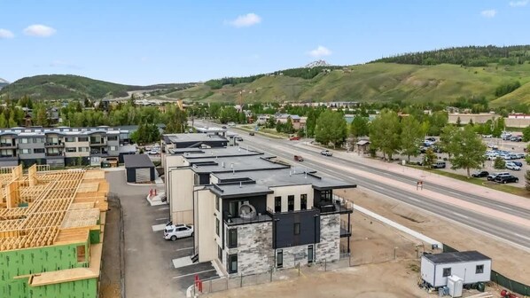 Un immeuble à plusieurs étages avec un parking et une route en arrière-plan.
