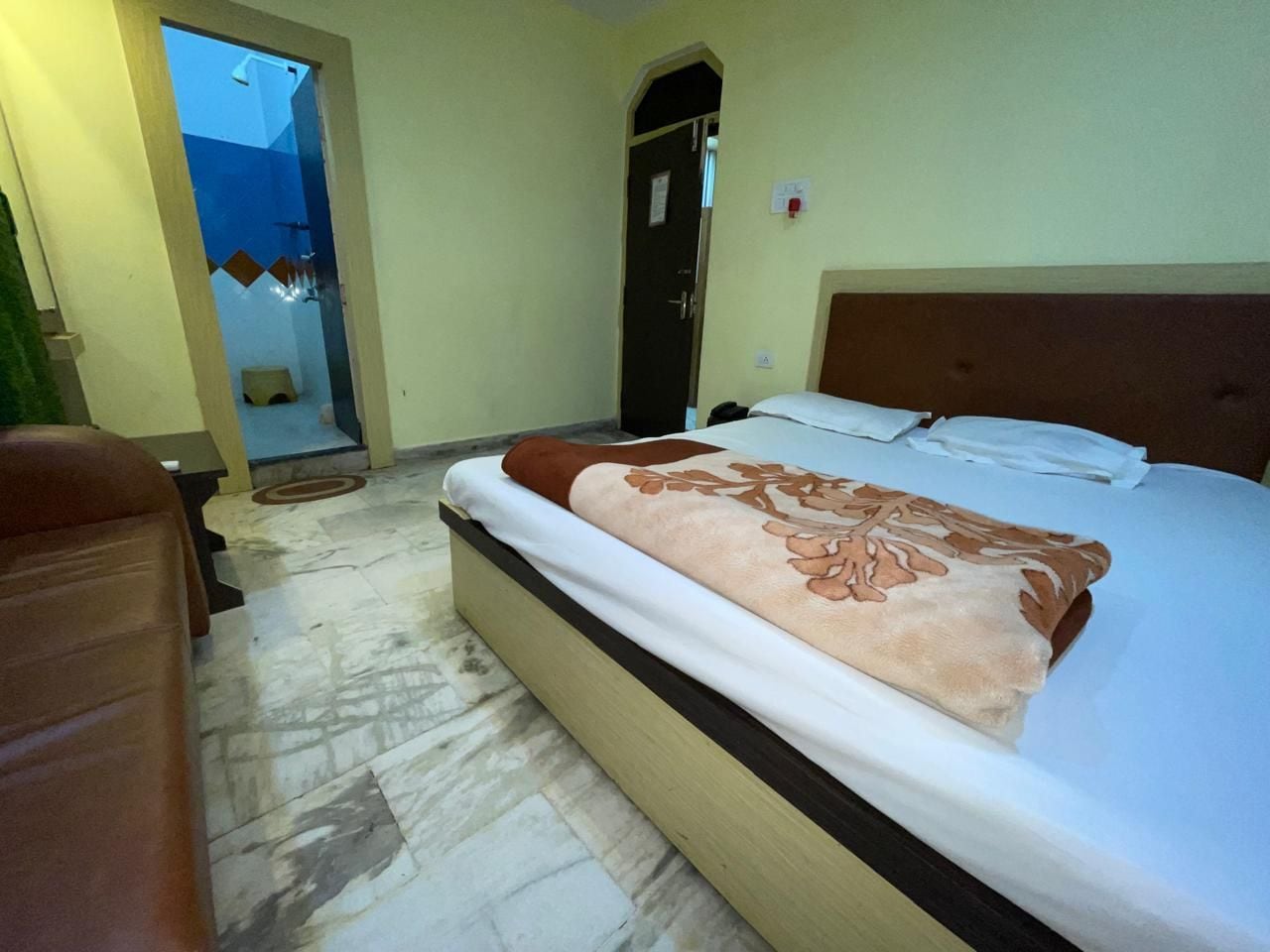 A hotel room with a bed, a door, and a small bathroom area.