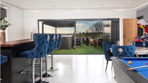Un espace intérieur moderne comprenant une table de billard, un bar et des coins salon.