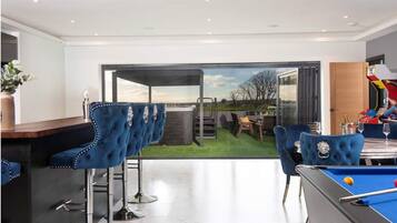 A modern indoor space with a pool table, bar area, and seating.