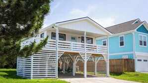 A two-story house with a covered porch and a fenced backyard. - Newly Updated Cottage in the Heart of KDH! (Kill Devil Hills)