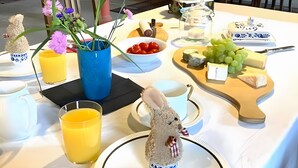 A dining table with a variety of food items, a decorative bunny, and a vase with flowers.