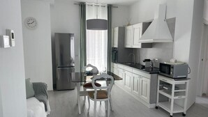 Une cuisine moderne avec des meubles blancs, un réfrigérateur en acier inoxydable, un four à micro-ondes et une machine à café.