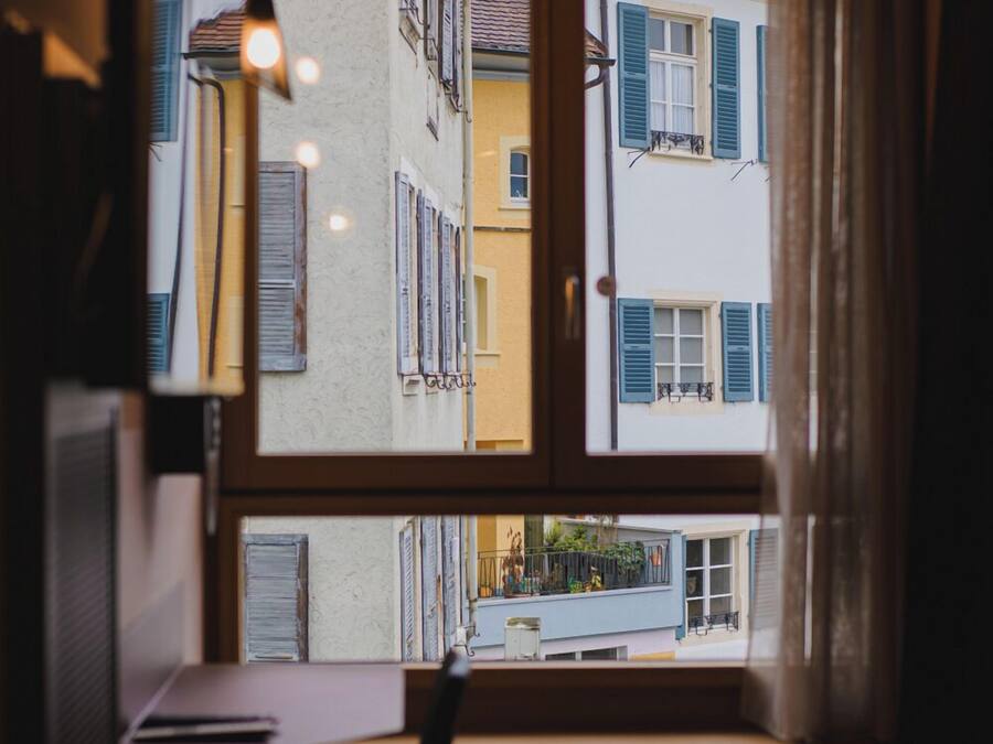 A room with a window overlooking a street, a desk, and a chair.