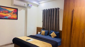 A bedroom with a bed, a wooden wardrobe, a painting on the wall, and an air conditioning unit. - Hotel The Silver Nest (Nagpur)