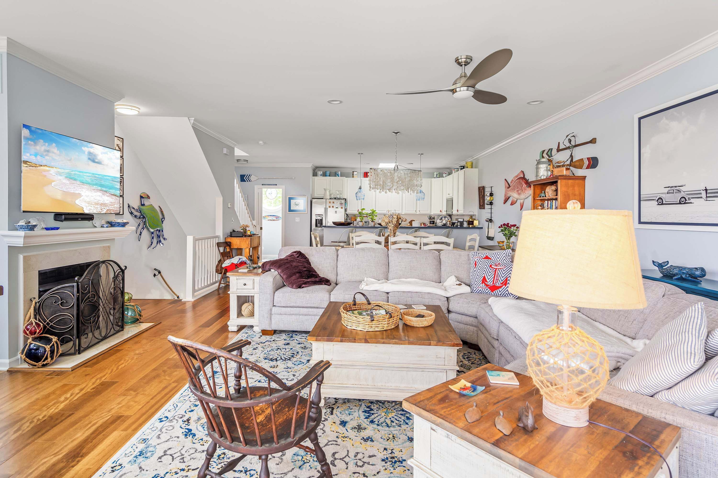 A spacious living room with a fireplace, a large television, and a ceiling fan.