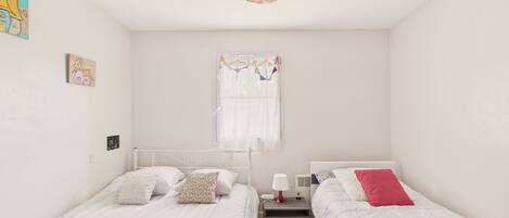Un dormitorio con dos camas, una mesita de noche, una lámpara y una luz decorativa colgante.