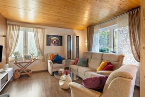 Un salon chaleureux avec un plancher en bois, une table basse en verre, un canapé beige et un meuble pour la télévision.