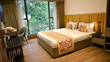 A hotel room with a large bed, a desk, and a chair.