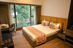 A hotel room with a large bed, a desk, and a chair. - Urvi Banquets & Guest House  (Bidhannagar)