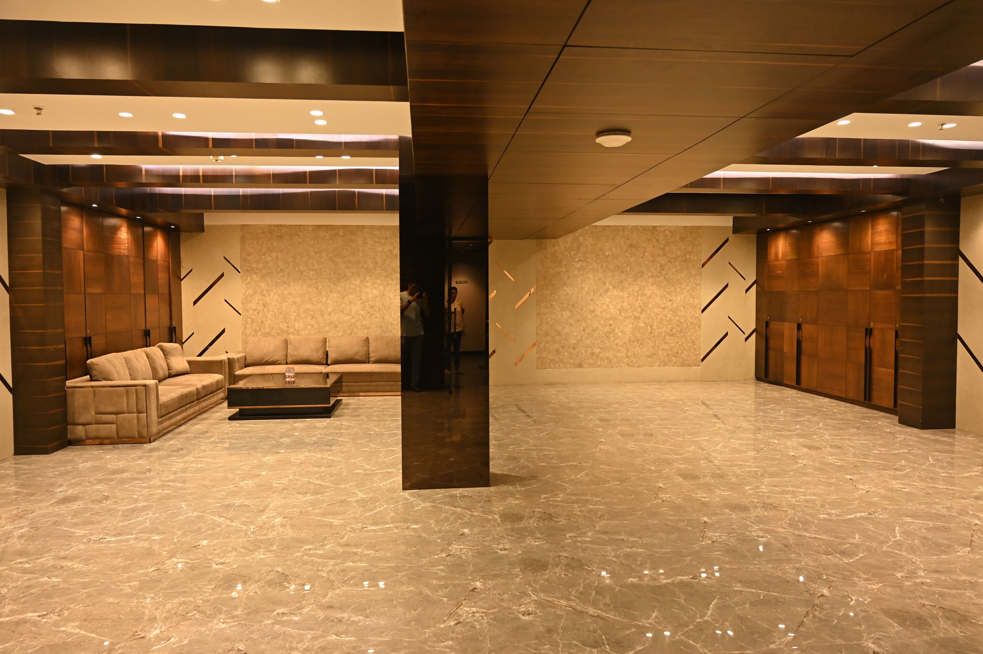 A spacious lobby with a marble floor, a sofa, and a large pillar.
