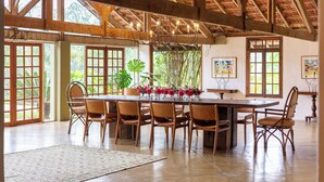 A spacious dining area with a large wooden table and chairs, surrounded by large windows and doors. - Fazenda Casa Grande: Tranquility, Nature and Fun for Family and Friends, (Bairro da Angola Jacareí)