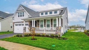 A two-story house with a stone facade, a front porch, and a garage. - Wild Air Getaway For 12! (Frankford)