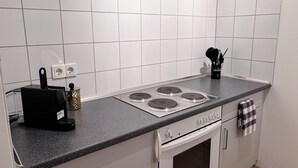 A kitchen with white tiled walls, a black countertop, a stove, and a coffee maker. - Perfect for families, right in the center incl. elevator (Dortmund)