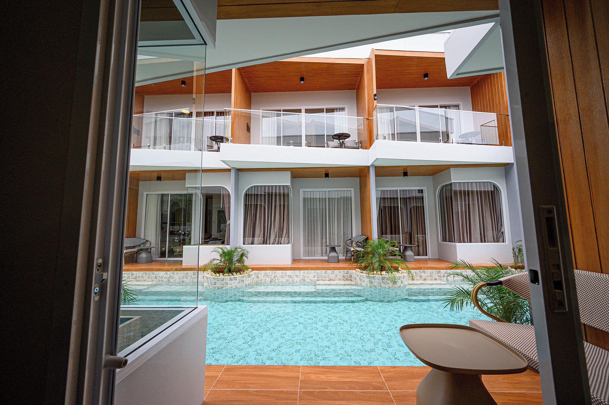 Un immeuble moderne à plusieurs étages, doté d’une piscine, de balcons et d’espaces de détente en plein air.