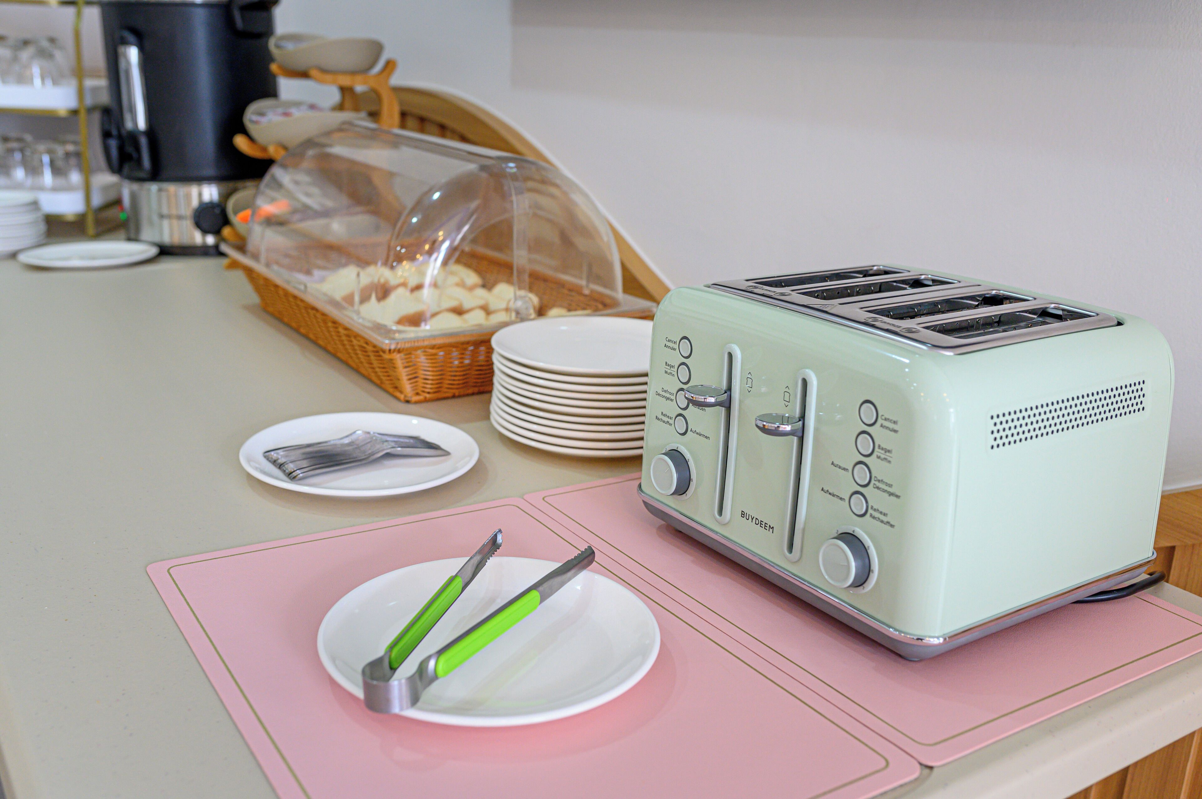 Una encimera de cocina con un tostador, una cesta de pan, platos y utensilios.