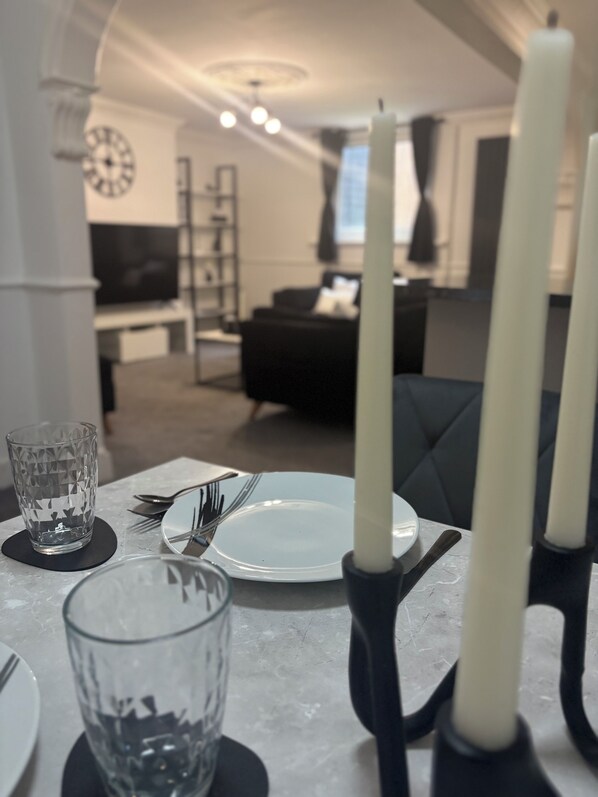 Een eettafel gedekt met borden, bestek en glazen, met een kandelaar in het midden.